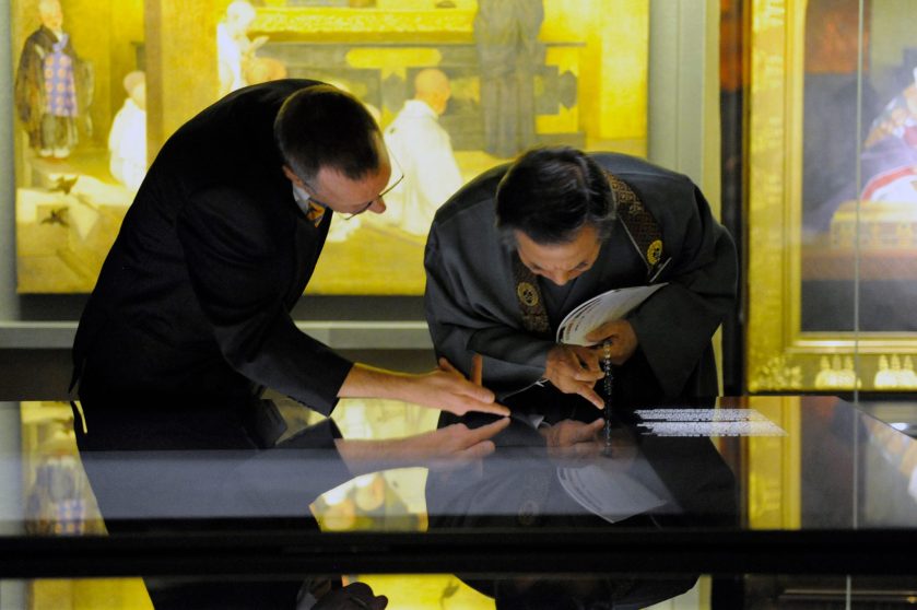 El Comisario de la exposición Jérôme Ducor (izquierda) con el Rev. Waji, administrador del Hongwanji, observando la vitrina de los libros.
